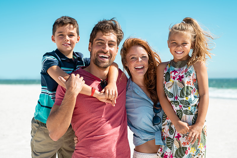 Smiling family of four standing together outdoors | Bright Orthodontics in Oshkosh, WI