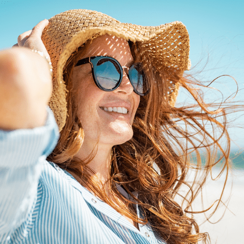 Smiling woman wearing sunhat and sunglasses outdoors | Bright Orthodontics in Oshkosh, WI